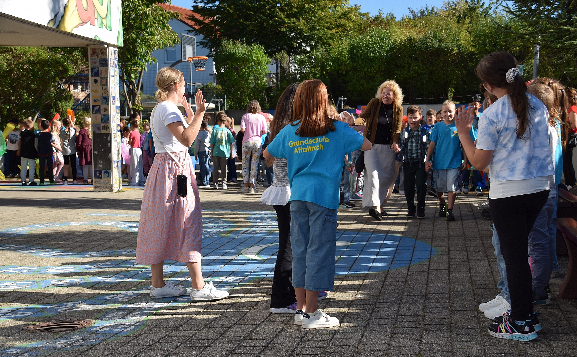 Foto von den Erstklässlern und ihren Paten, wie sie durch das Spalier der anderen Kinder laufen